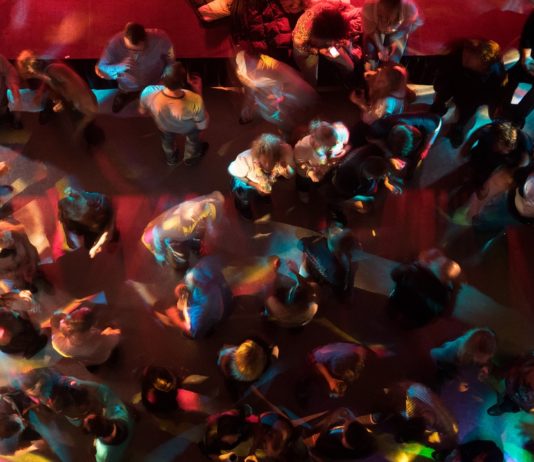 Zahlreiche Menschen tanzen und stehen in einer Bar oder in einer Disco