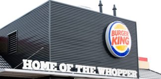 Eine Burger King Filiale mit einer modernen Fassade in edlem Schwarz. Im Fokus liegen der Slogan, das Logo sowie das Werbeplakat an der Hausfassade.