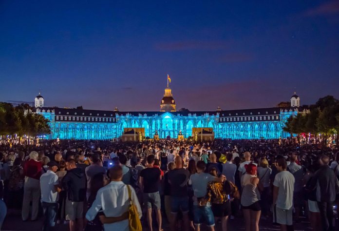 Schlosslichtspiele nachts Menschen Zuschauer Schloss Lichtspiele Show Event Großereignis Die Schlosslichtspiele in Karlsruhe. Die große Zuschauermenge steht vor dem Karlsruher Schloss bei Nacht und blickt auf die Lichter und Shows. Der Nachthimmel ist dunkelblau.