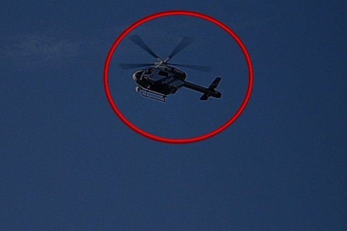 Ein Hubschrauber am Abend. Der Helikopter fliegt über einer Stadt und ist auf der Suche nach Personen oder mitten im Einsatz. Mittlerweile ist es dunkel geworden und der Hubschrauber muss Licht einsetzen.