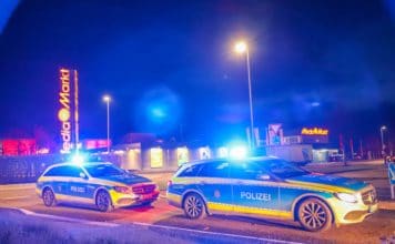Mehrere Polizeiwagen fahren mit Blaulicht durch die Nacht.