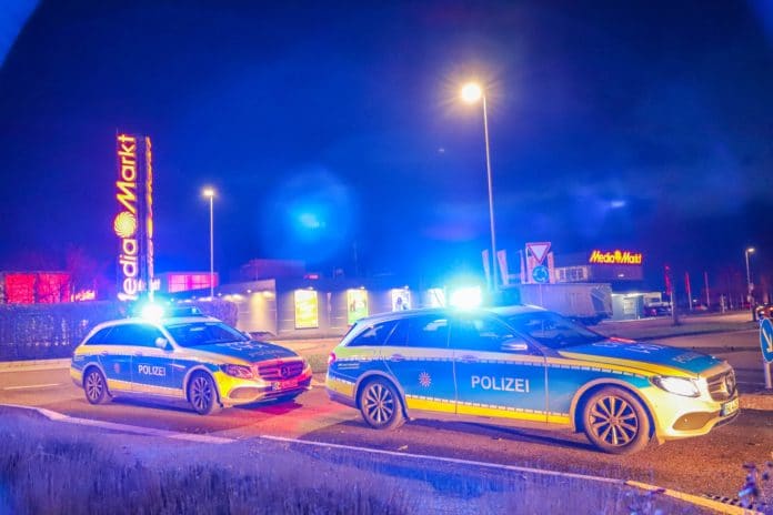Mehrere Polizeiwagen fahren mit Blaulicht durch die Nacht.