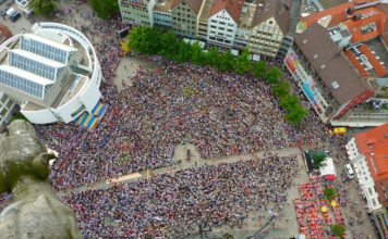 Menschenmasse in der Innenstadt. Zahlreiche Menschen versammeln sich zu einer Kundgebung oder einer Demo auf einem großen Platz. Tausende Teilnehmer sind friedlich zusammen gekommen.