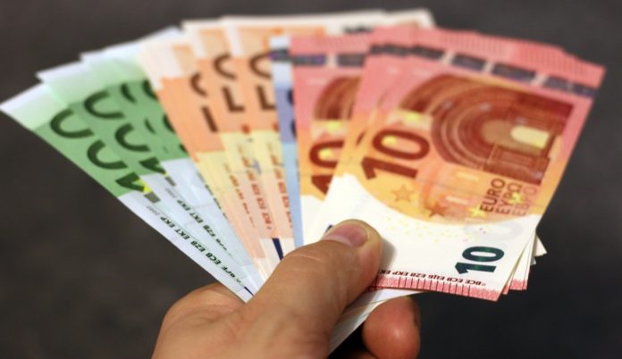 Eine Person hält Geld in der Hand. Der Mensch hält mehrere 100-, 50-, 20- und 10-Euro-Scheine aufgefächert zwischen den Fingern.