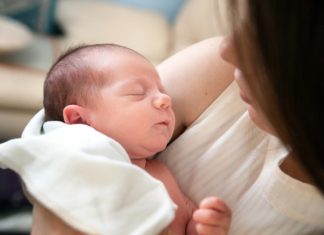 Neugeborenes Baby im Arm einer Mutter und am kuscheln