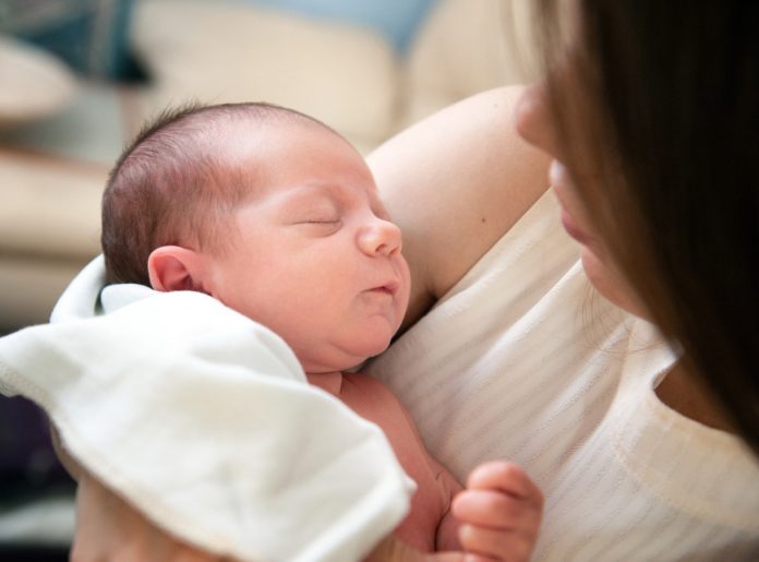 Neugeborenes Baby im Arm einer Mutter und am kuscheln