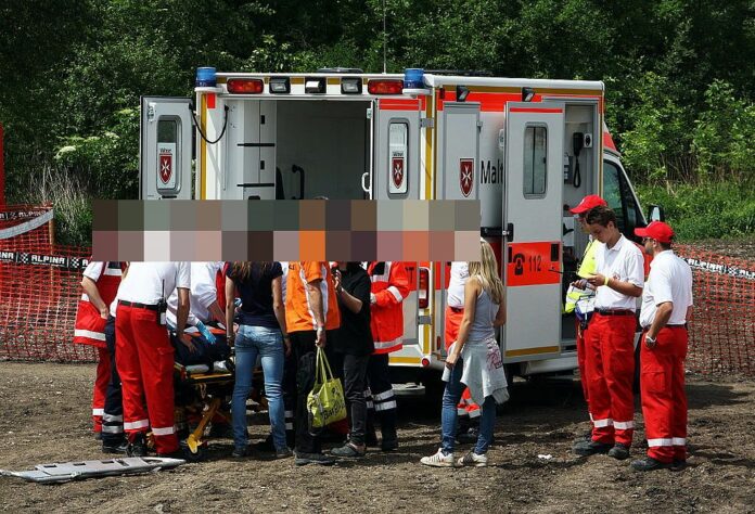 Rettungseinsatz mit Krankenwagen. Die Rettungskräfte stehen am Krankenwagen und machen die Erstversorgung des Patienten. Dann fährt der Einsatzwagen ins Krankenhaus.