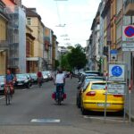 Mehrere Fahrradfahrer fahren mitten auf der Sophienstraße in Karlsruhe. Zu beiden Seiten sind eine Menge Autos geparkt. Ein Schild an der Seite sowie eines, das auf die Straße aufgemalt ist, weist darauf hin, dass es sich um eine Fahrradstraße handelt.