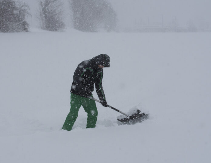 Mann am Schnee schaufeln.