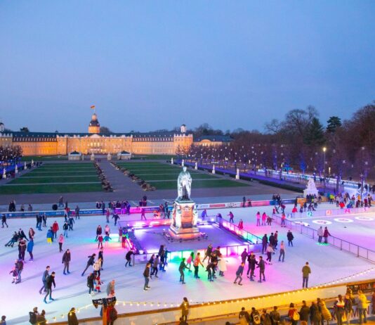 Die Eiszeit vorm Karlsruher Schloss. Die Bürger laufen Schlittschuh auf einer großen Eisfläche vor dem Schloss in Karlsruhe. Es ist Abendstimmung und die Eisfläche ist bunt beleuchtet.