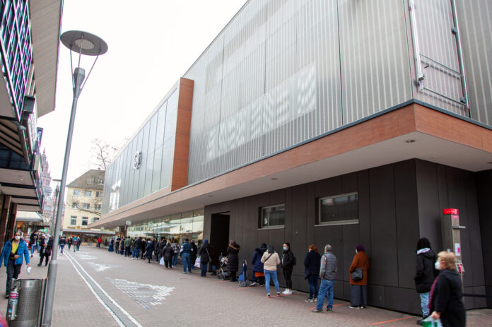 Lange Schlange auf Straße vor Geschäft