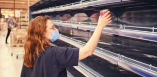 Leeres Regal im Supermarkt mit Mitarbeiterin