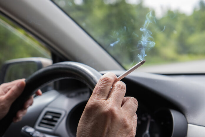 Person raucht im Auto