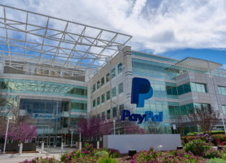 Das Paypal Hauptquartier erstrahlt mit seinen vielen gläsernen Elementen in sonnigem Wetter. Der gepflegte Garten und der blaue Himmel ergeben ein angenehmes Gesamtbild.