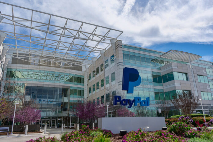 Das Paypal Hauptquartier erstrahlt mit seinen vielen gläsernen Elementen in sonnigem Wetter. Der gepflegte Garten und der blaue Himmel ergeben ein angenehmes Gesamtbild.
