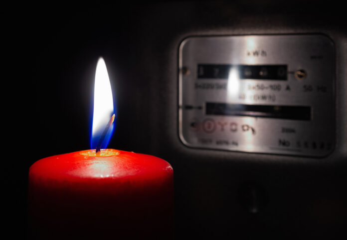 Eine Kerze wird bei Stromausfall im Dunklen vor dem Stromzähler angezündet