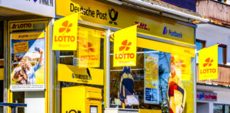 Der Eingang eines Totto Lotto Kiosk mit einem Postkasten und hängenden Lottofahnen.