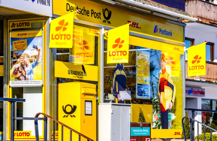 Der Eingang eines Totto Lotto Kiosk mit einem Postkasten und hängenden Lottofahnen.