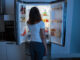 Frau steht vor Kühlschrank