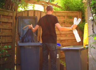 Ein Mann trennt seinen Abfall ind Restmüll und Plastik