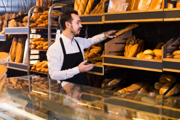 Ein Mann räumt ein Regal in einer Bäckerei ein.
