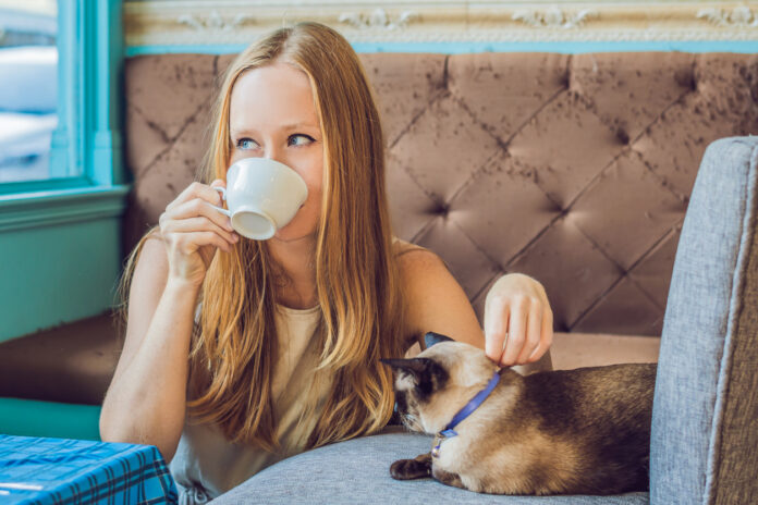 Eine Frau trinkt im Katzencafé einen Kaffee.