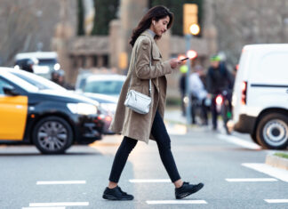 Eine Frau geht über die Straße und schaut auf ihr Handy.