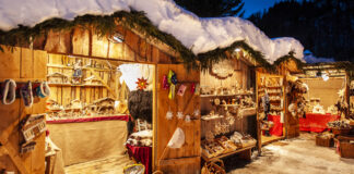 Ein verschneiter Weihnachtsmarkt mit Holzhütten.