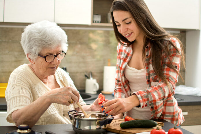 Großmutter und junges Mädchen kochen gemeinsam.