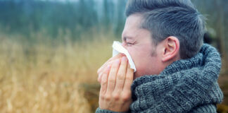 Ein Mann mit Winterschal putzt sich die Nase.