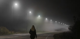 Eine Frau geht in der Nacht eine Straße entlang.