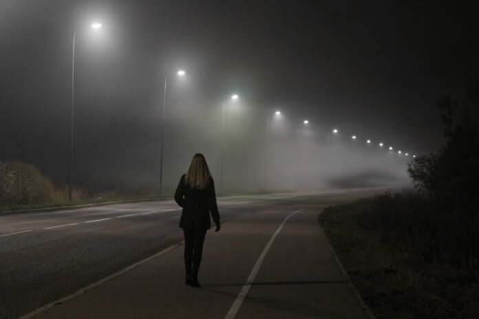 Eine Frau geht in der Nacht eine Straße entlang.