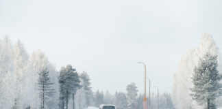 Ein Auto fährt auf einer verschneiten Straße.