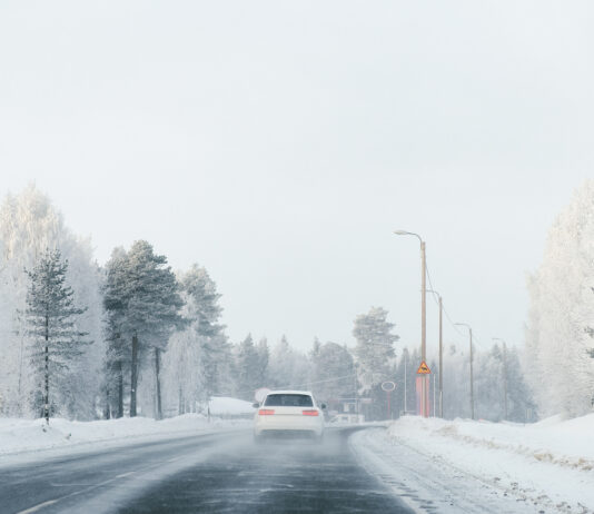 Ein Auto fährt auf einer verschneiten Straße.