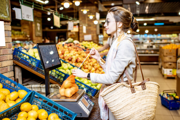 Eine Frau wiegt Äpfel im Supermarkt
