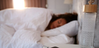 Schlafende Frau mit Handy beim Bett.