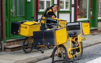 Ein Postbote liefert Briefe mit dem Fahrrad aus.