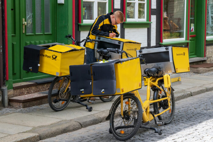 Ein Postbote liefert Briefe mit dem Fahrrad aus.
