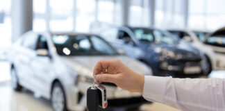 Verkäufer hält Schlüssel zu neuem Auto in die Höhe.