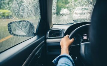 Ein Autofahrer fährt im Regen. Beide Hände umfassen fast das Lenkrad. Der Fahrer fährt sehr konzentriert, denn die Wetterbedingungen sind alles andere als gut. Durch die Windschutzscheibe kann er aber alles gut sehen.