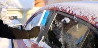 Eine Person kratzt das Eis von einem Autofenster im Winter