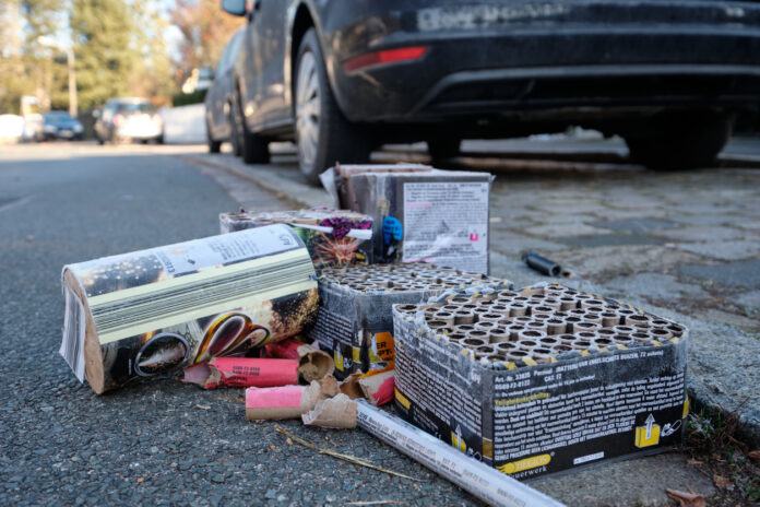 Der Müll von Silvesterböllern liegt auf der Straße neben einem Auto.