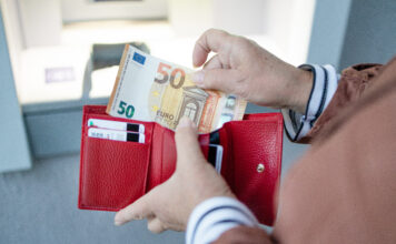 Eine Frau holt Geld aus ihrem Geldbeutel.