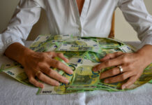 Eine Frau umarmt einen Stapel Geld.