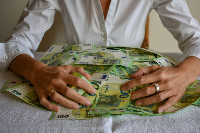 Eine Frau umarmt einen Stapel Geld.