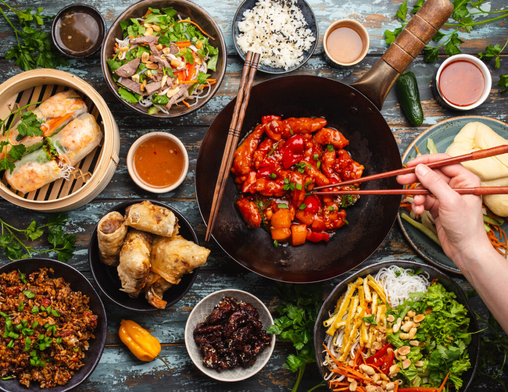 Verschiedene chinesische Gerichte werden angerichtet und mit Stäbchen gegessen. 