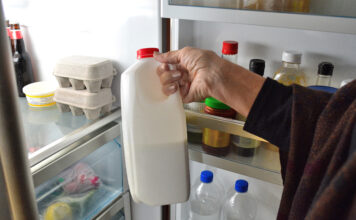 Eine Frau nimmt eine Flasche Milch aus dem Kühlschrank.
