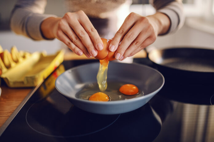 Eine Person schlägt ein Ei in eine Pfanne