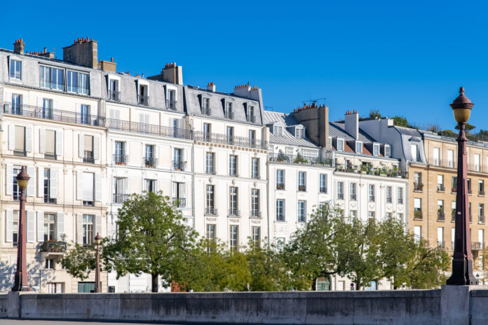 Häuserfassade in Paris mit Bäumen am unteren Bildrand