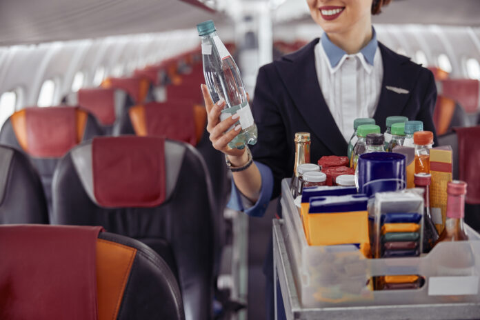 Flugbegleiterin schenkt Wasser aus.